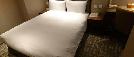 Una cama bien hecha con ropa blanca en una habitación de hotel.