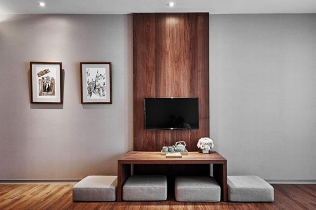 Een moderne woonkamer met een houten tv-meubel, een flatscreen-tv en twee ingelijste kunstwerken aan de muur.