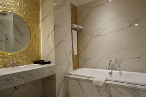 Un baño con lavamanos de mármol, bañera y espejo.