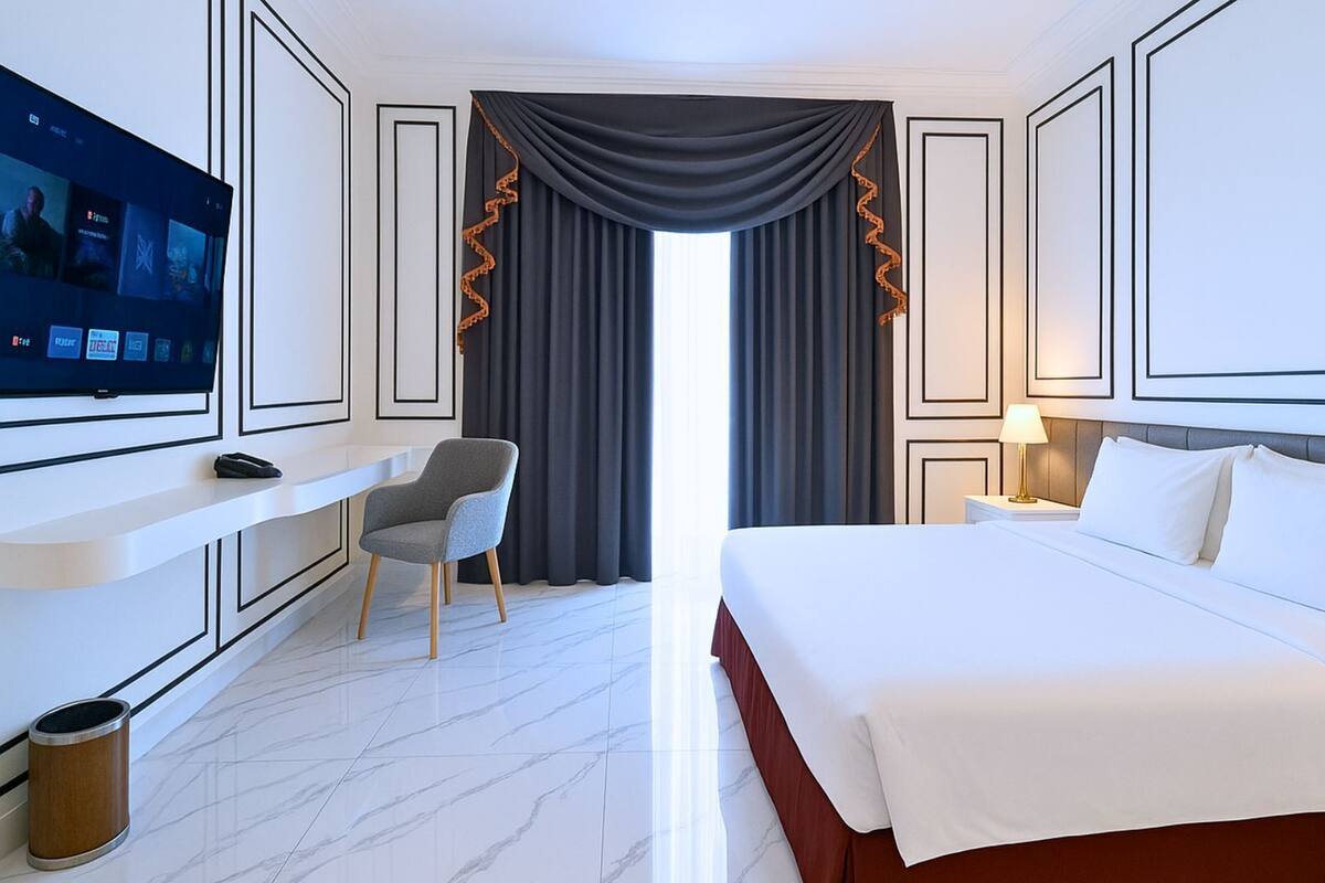 Une chambre d’hôtel comprenant un lit, un bureau avec une télévision, une chaise et une table de chevet avec une lampe.
