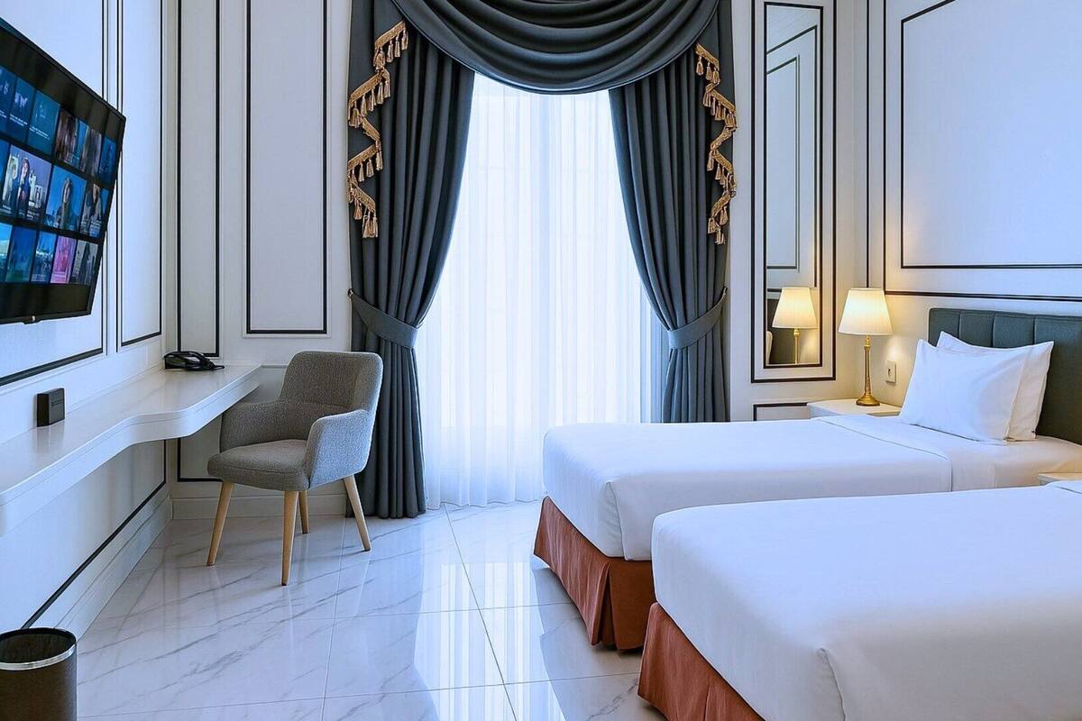 Une chambre d’hôtel avec deux lits, une télévision, une chaise et un bureau.