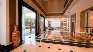Un vestíbulo amplio con piso de mármol, ventanas grandes y jarrones decorativos.