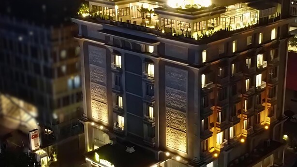 Un edificio de varios pisos con balcones iluminados y una terraza en la azotea.