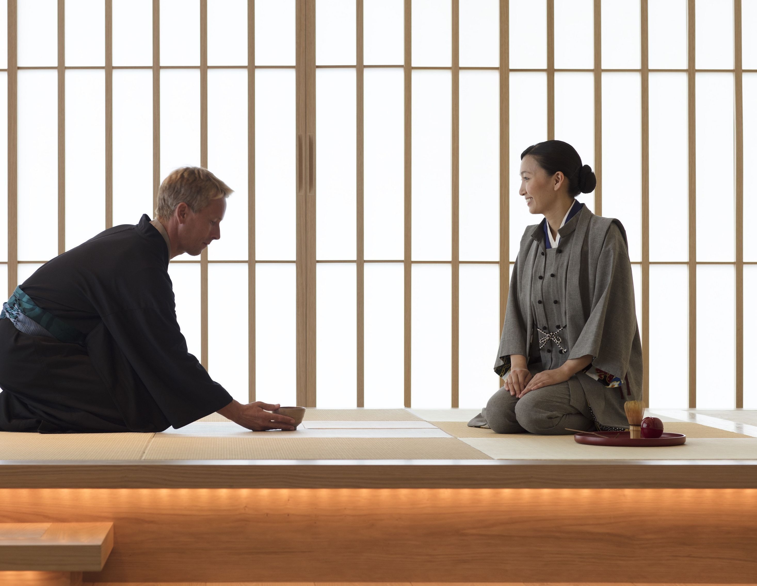 A traditional Japanese room with tatami flooring, a low wooden table, and shoji screens in the background.