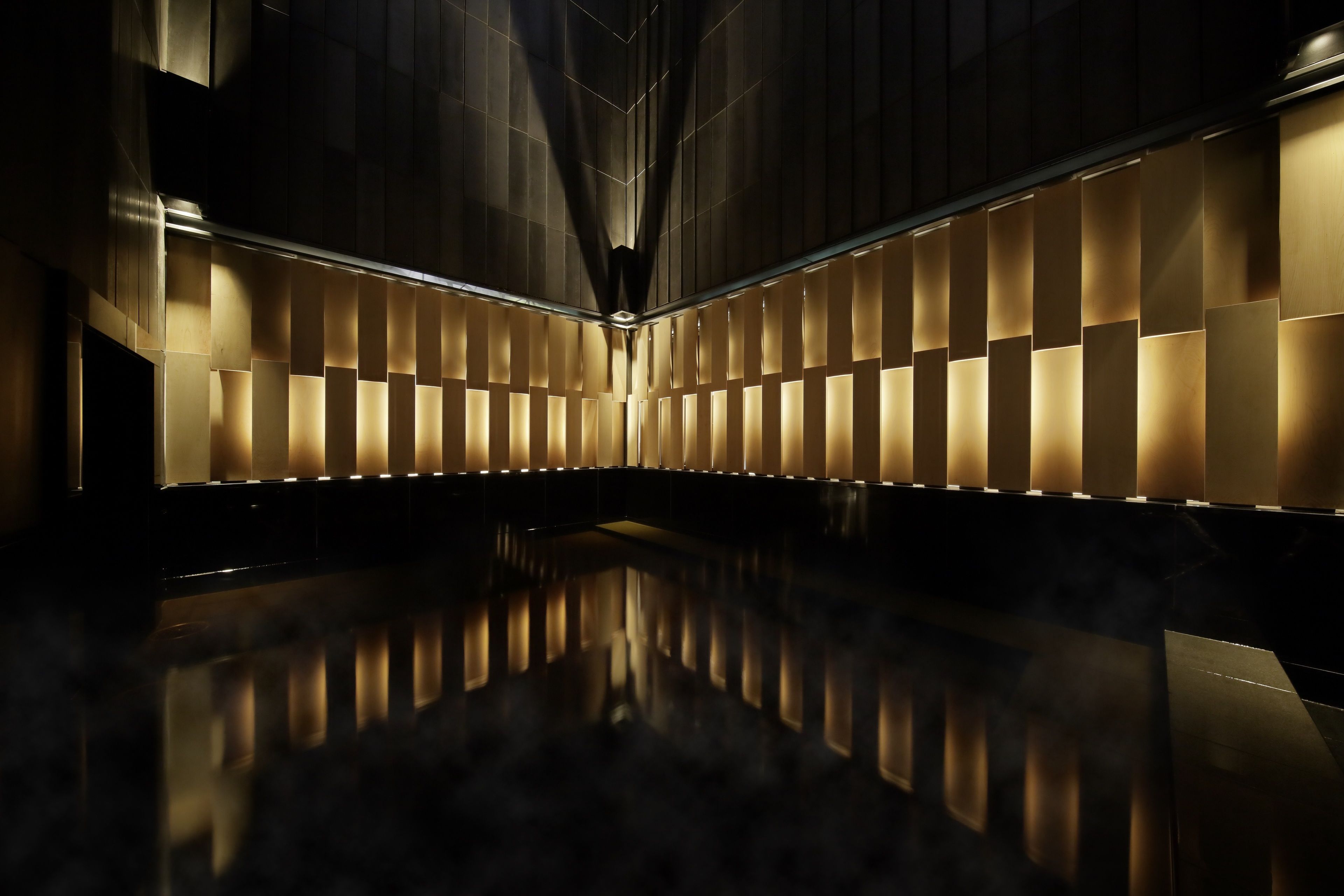 A modern interior with a reflective floor and illuminated panels on the walls.