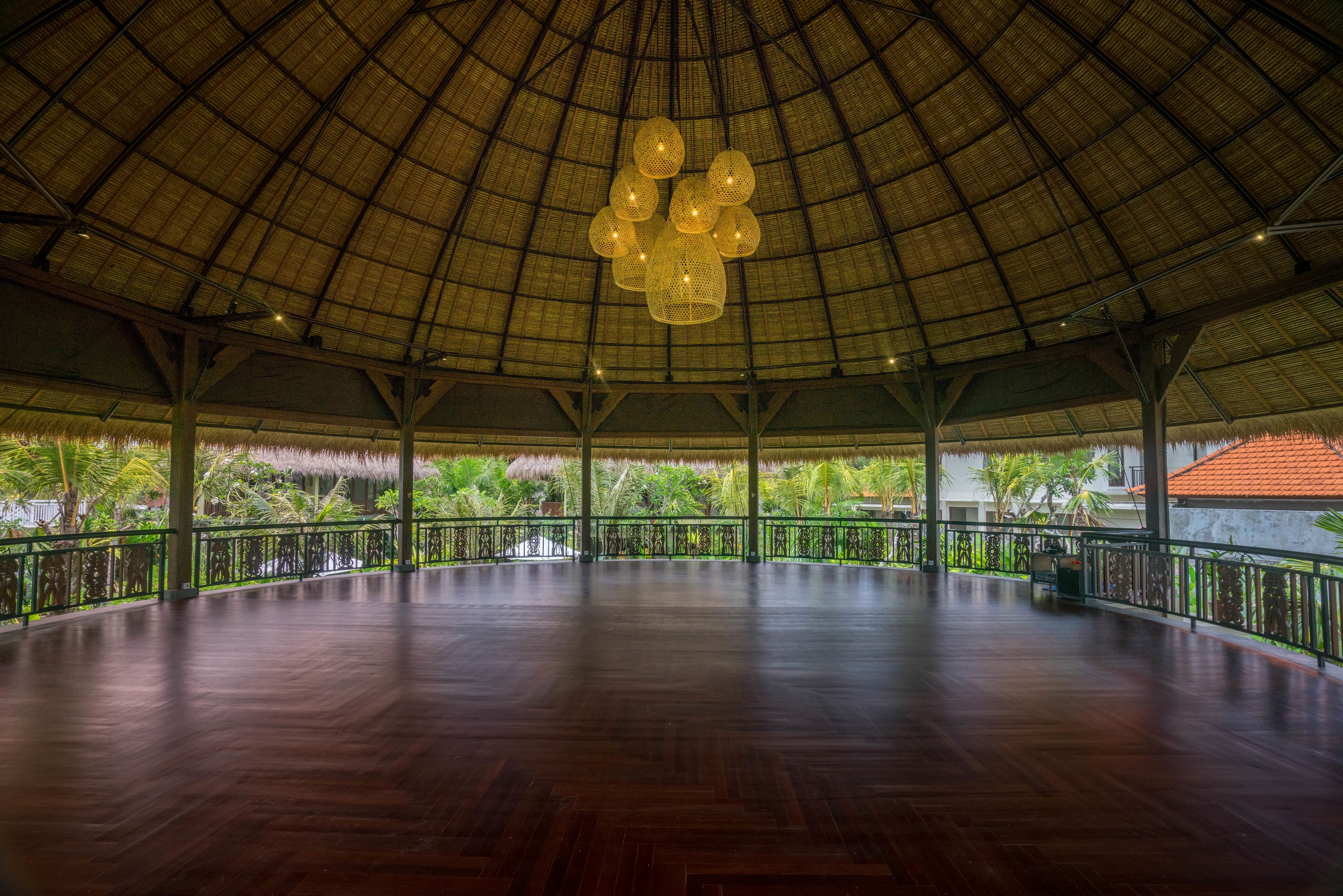 An open pavilion with a high, curved roof and a wooden floor.