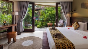 Habitación de hotel con cama, escritorio, silla y vistas a un jardín exuberante.