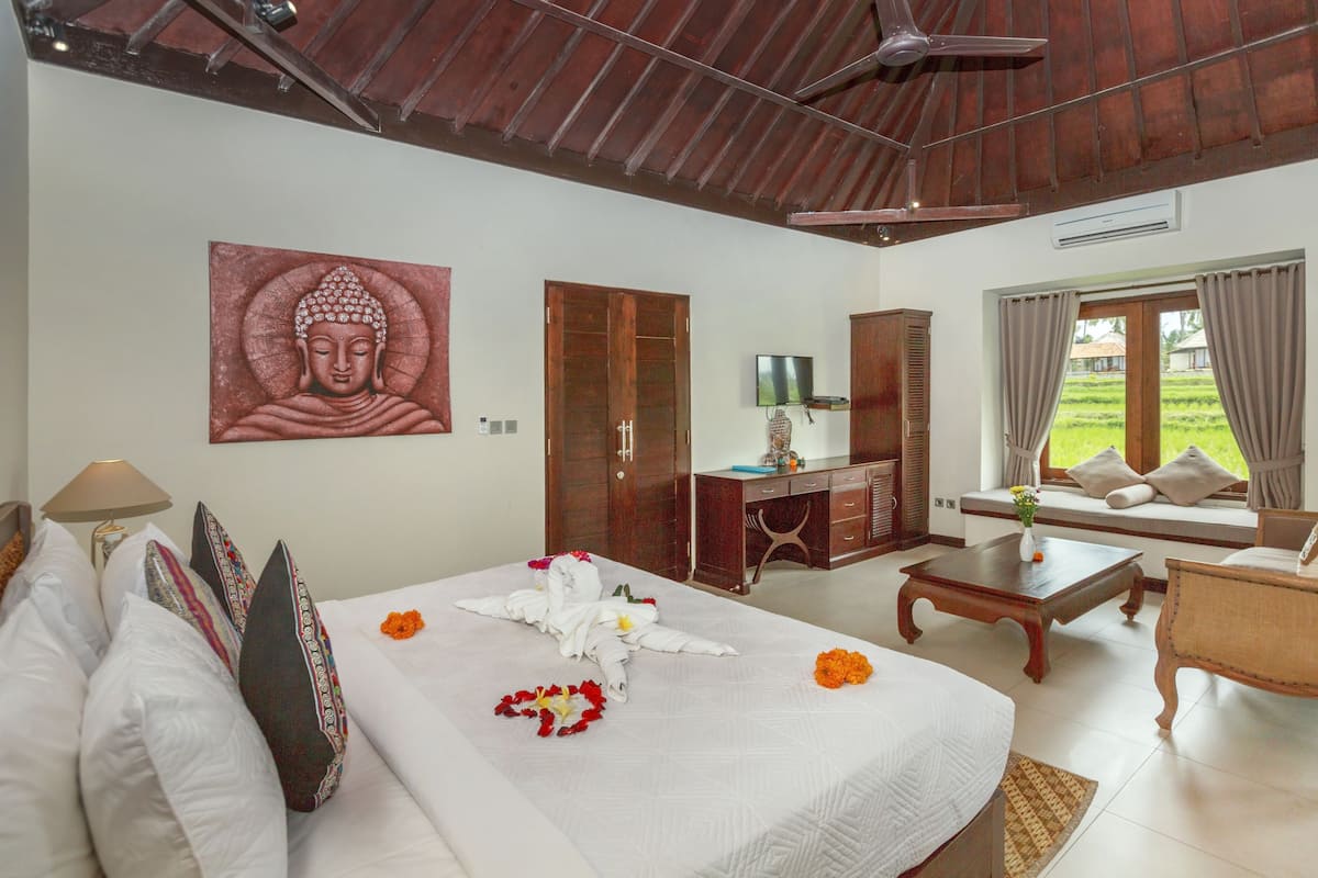 A hotel room with a bed, a desk, a sofa, and a Buddha painting.