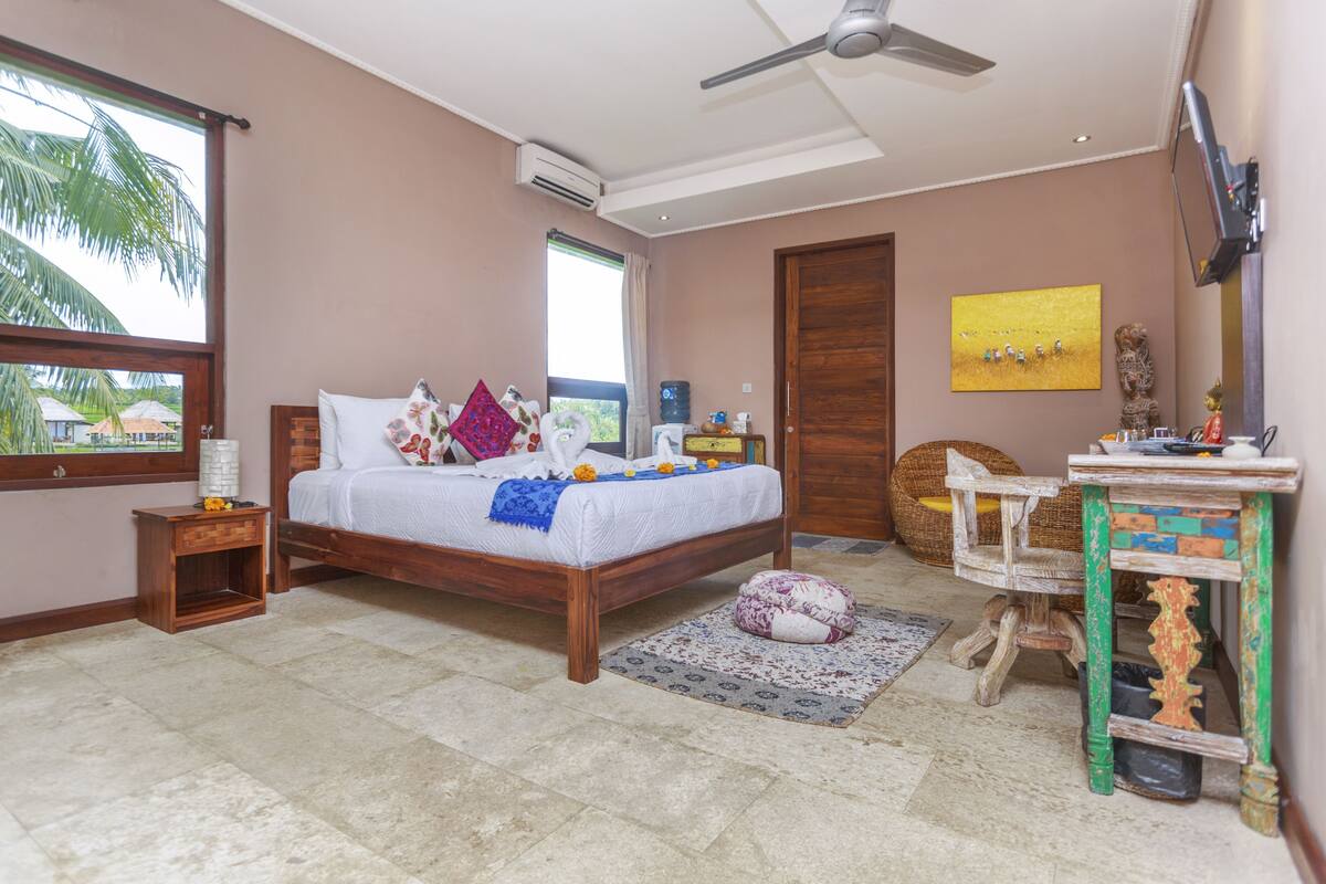A bedroom with a bed, bedside tables, a television, a window, and a door.