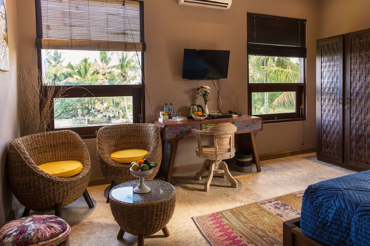 A room with wicker chairs, a desk, and a bed.