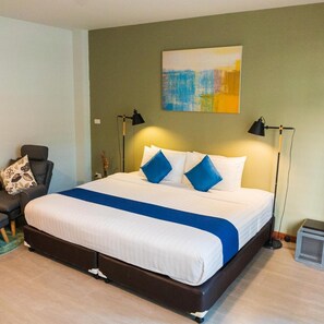 Ein Hotelzimmer mit einem großen Bett, zwei Nachttischlampen, einem Sessel und einem Wandbild.