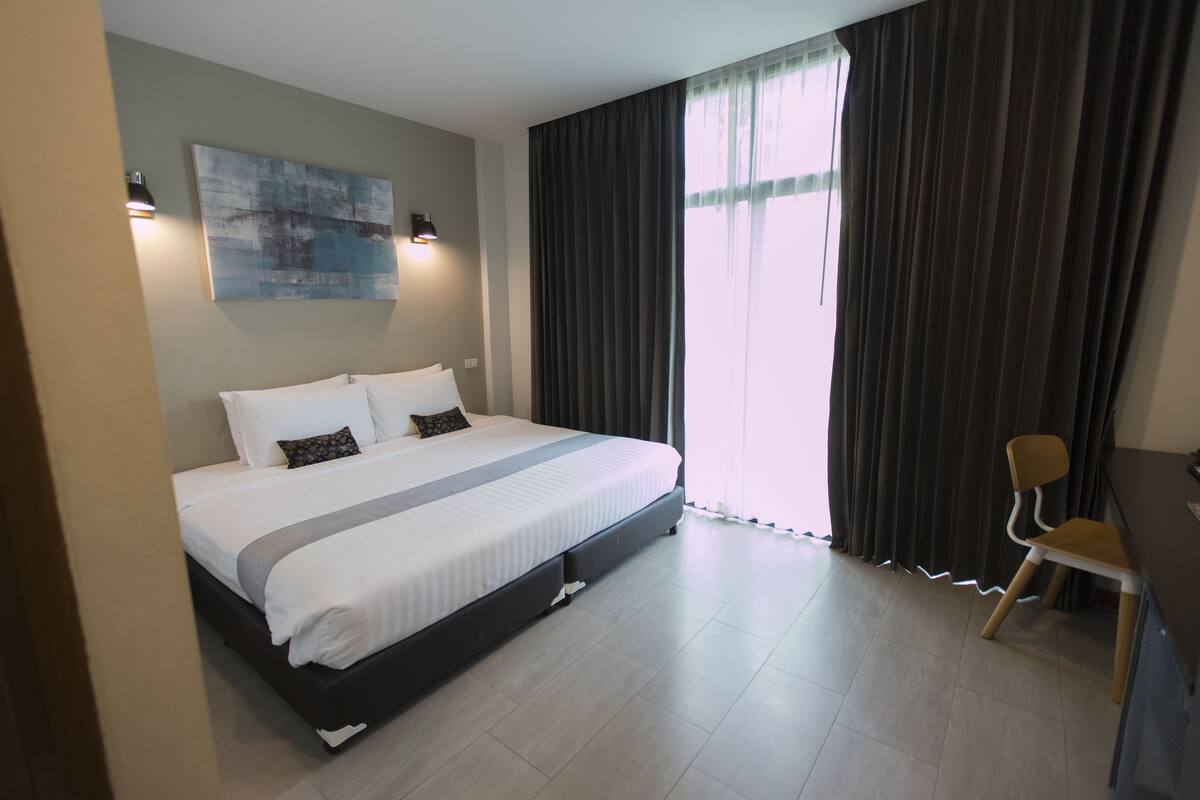 A modern hotel room with a large bed, a desk, and a chair.