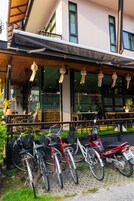 A restaurant with outdoor seating, bicycles, and a motorcycle parked outside.