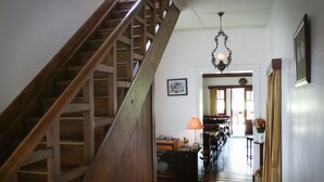 Un escalier menant à une salle à manger agrémentée d’un lustre, d’une table avec des chaises et d’un tableau accroché au mur.