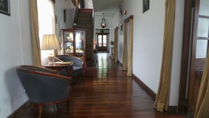 Un couloir avec un plancher en bois, un escalier, une lampe, une chaise et une table.