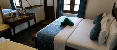 A hotel room with a bed, a desk, a mirror, and a window with curtains.