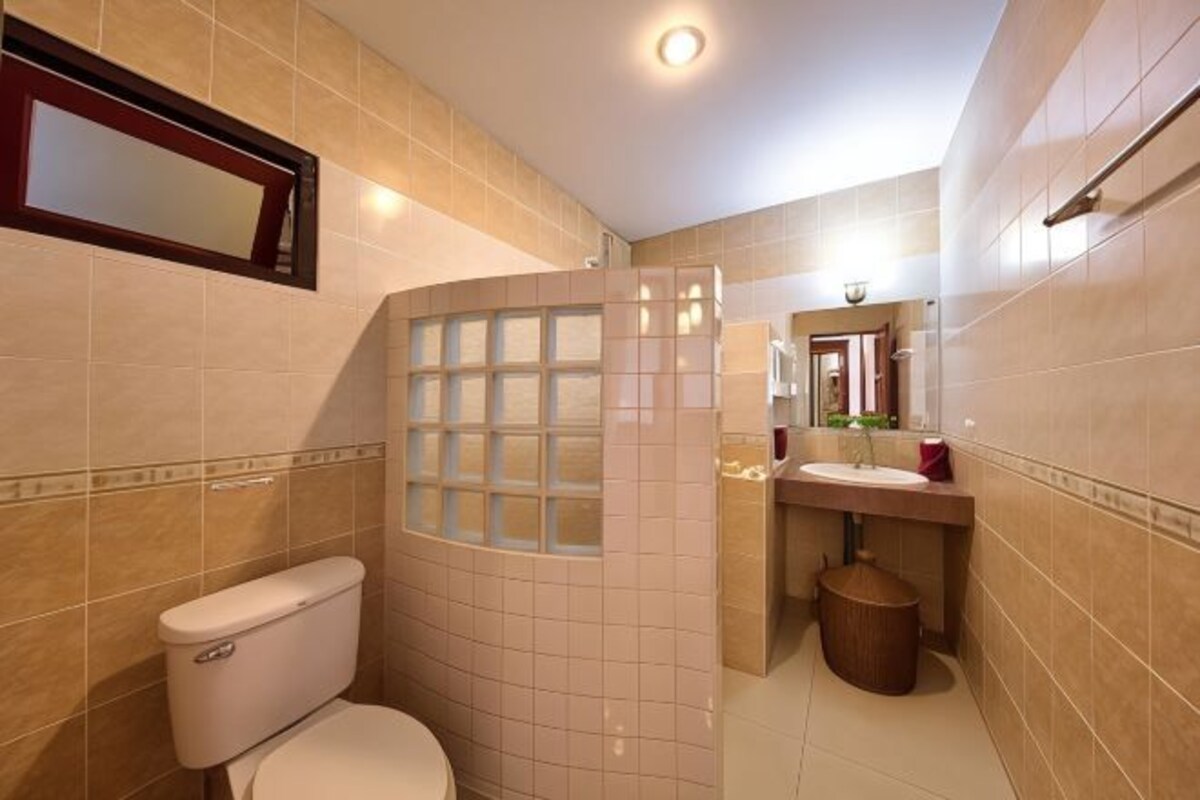 A bathroom with a toilet, a shower with a glass door, a sink, and a mirror.