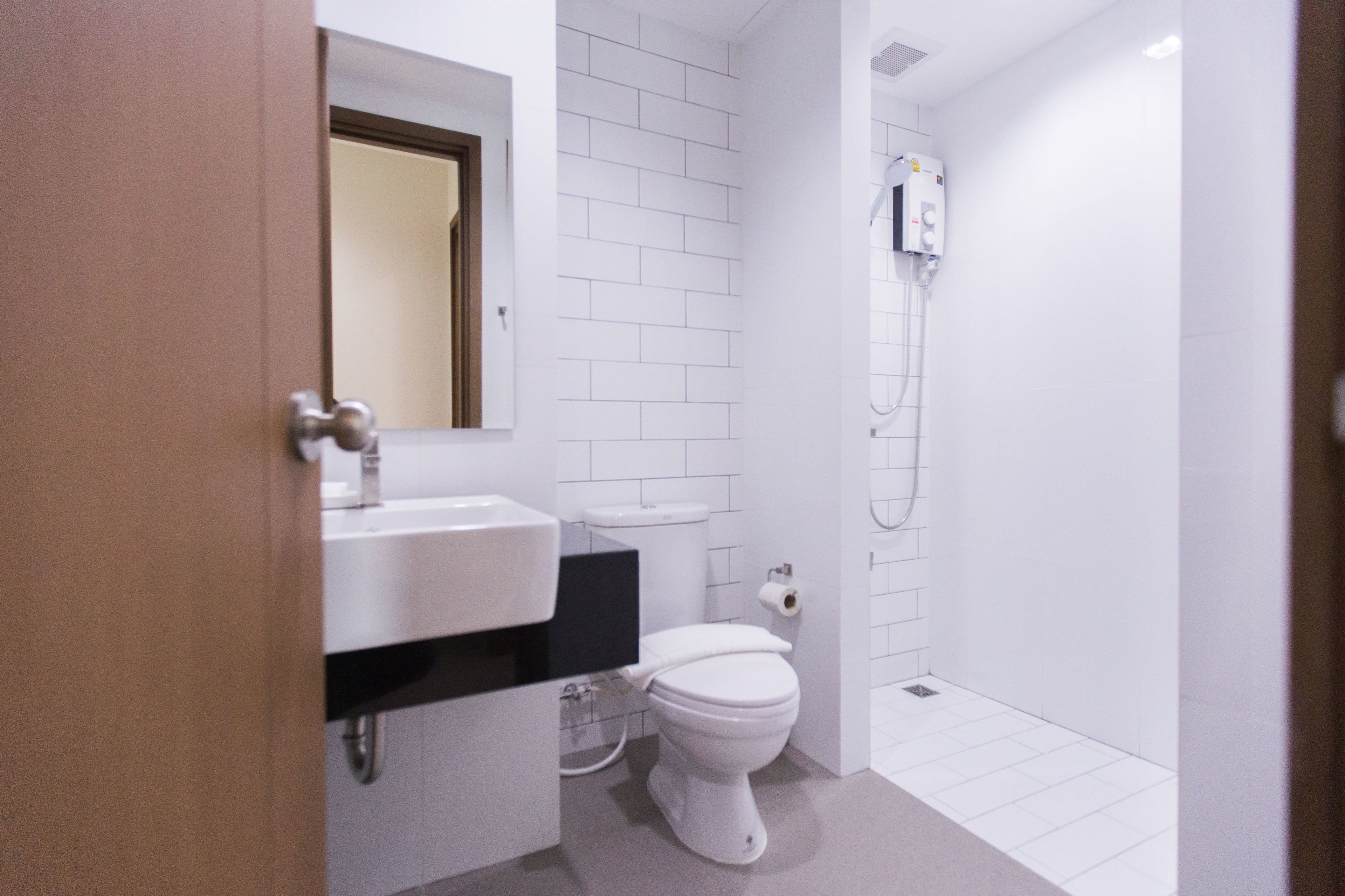 Un baño con lavamanos, inodoro y ducha blancos.