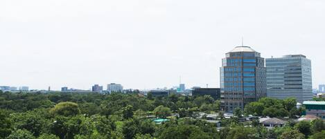 A cityscape with modern buildings and dense greenery.