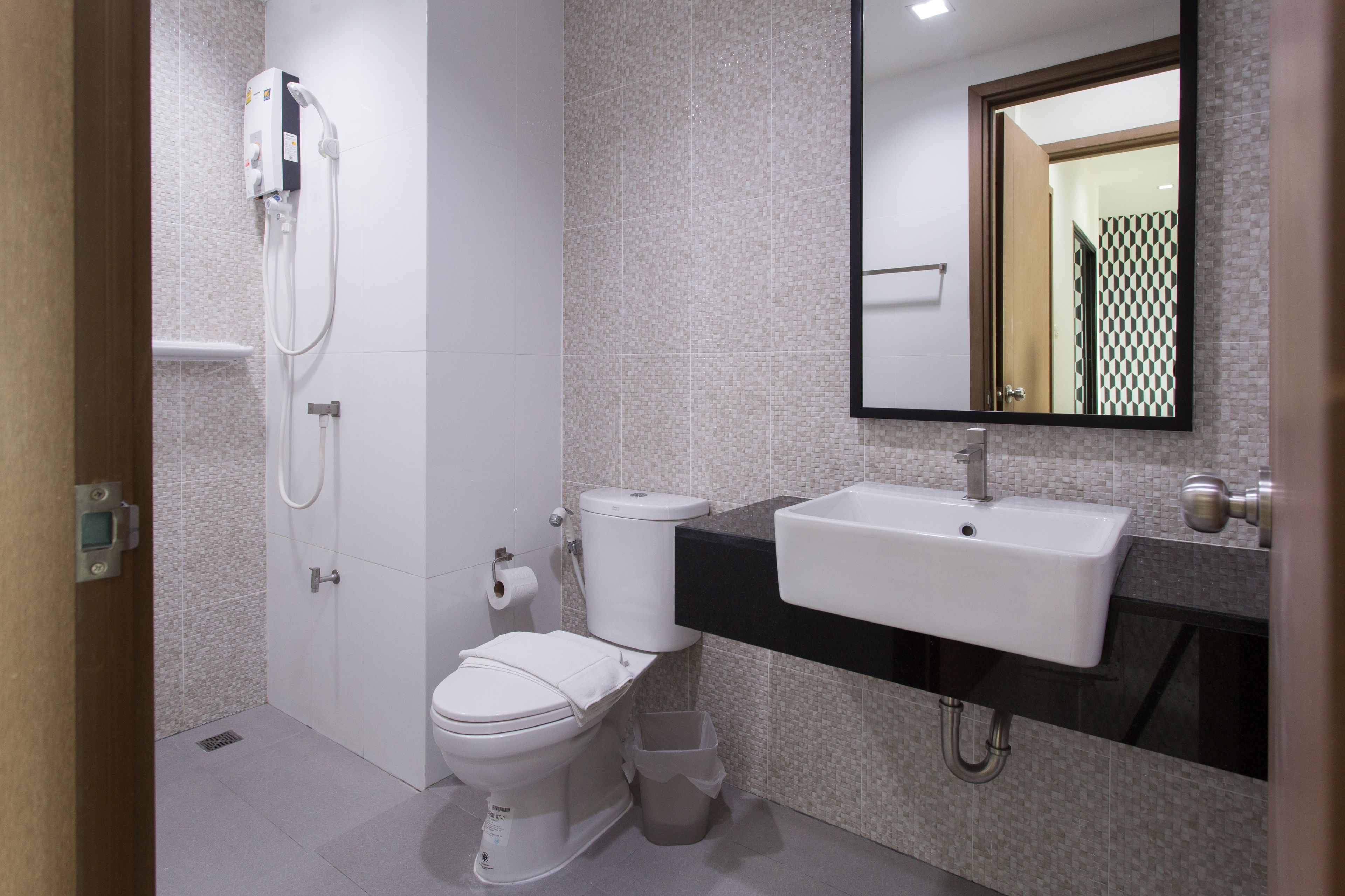 A modern bathroom with a toilet, bidet, sink, and mirror.