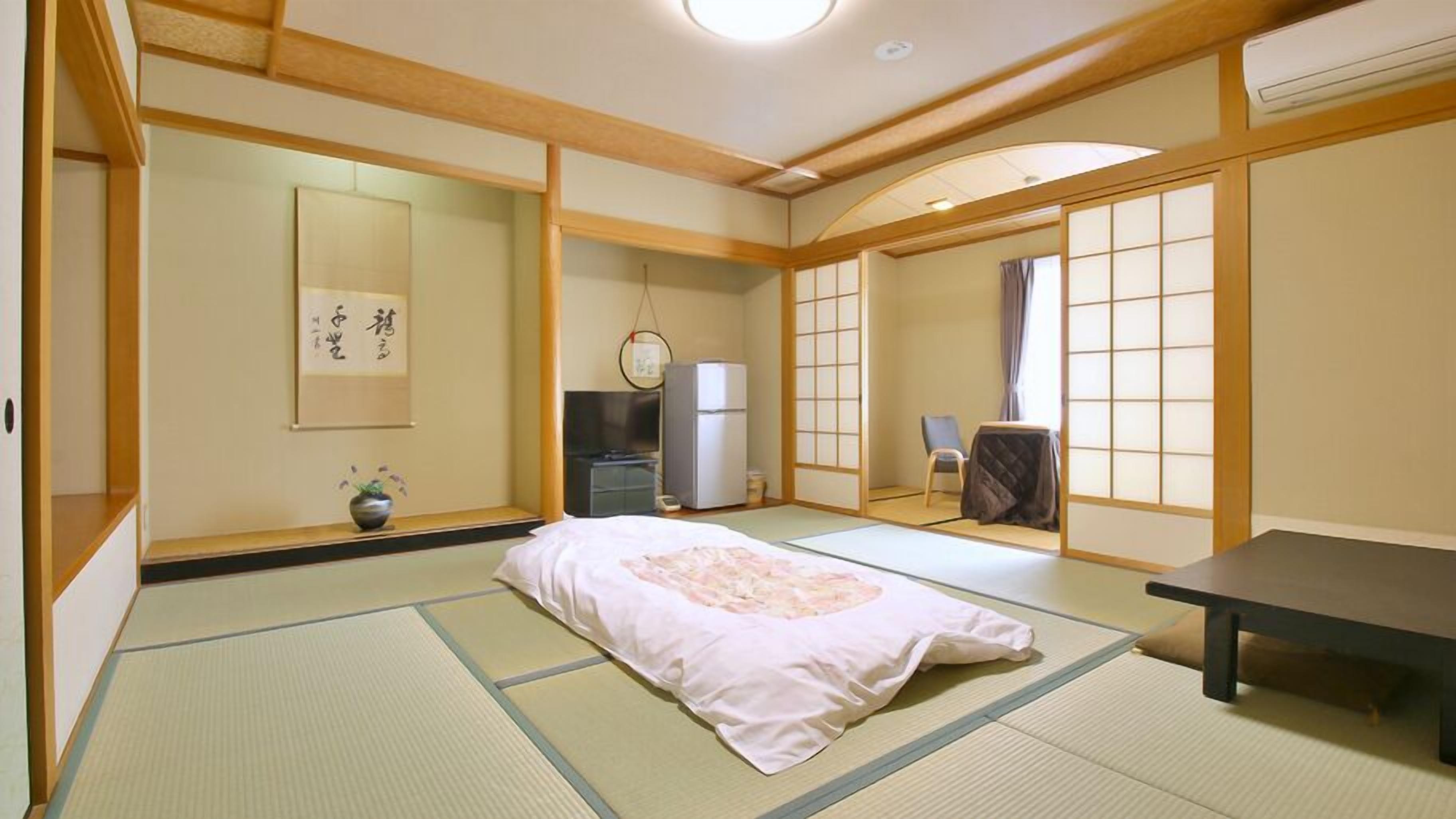 Une pièce de style japonais traditionnel, avec un sol recouvert de tatamis, un lit, un bureau et une porte coulissante.