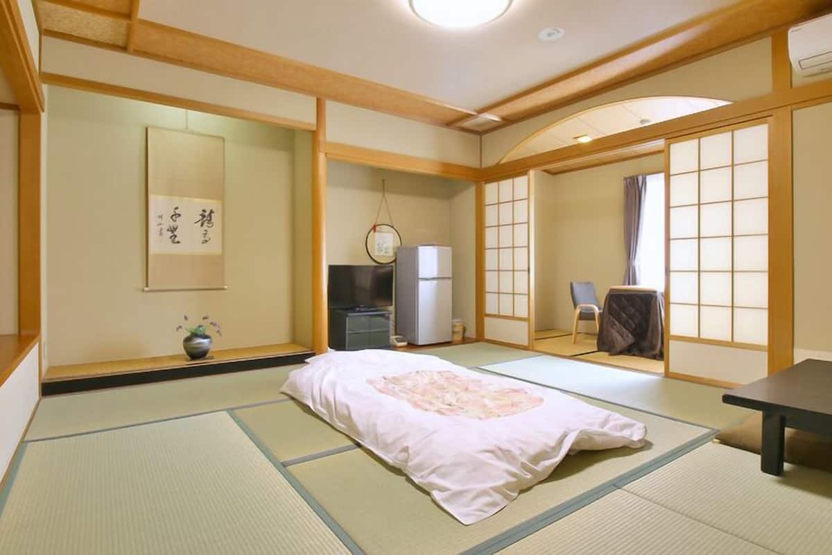Une pièce de style japonais traditionnel, avec un sol recouvert de tatamis, un lit, un bureau et une porte coulissante.