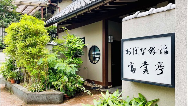 Un edificio japonés tradicional con un letrero y abundante vegetación.