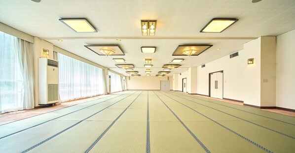 A long, empty hallway with tatami mat flooring, recessed lighting, and sliding doors on the right. - Misasa Royal Hotel (Misasa)
