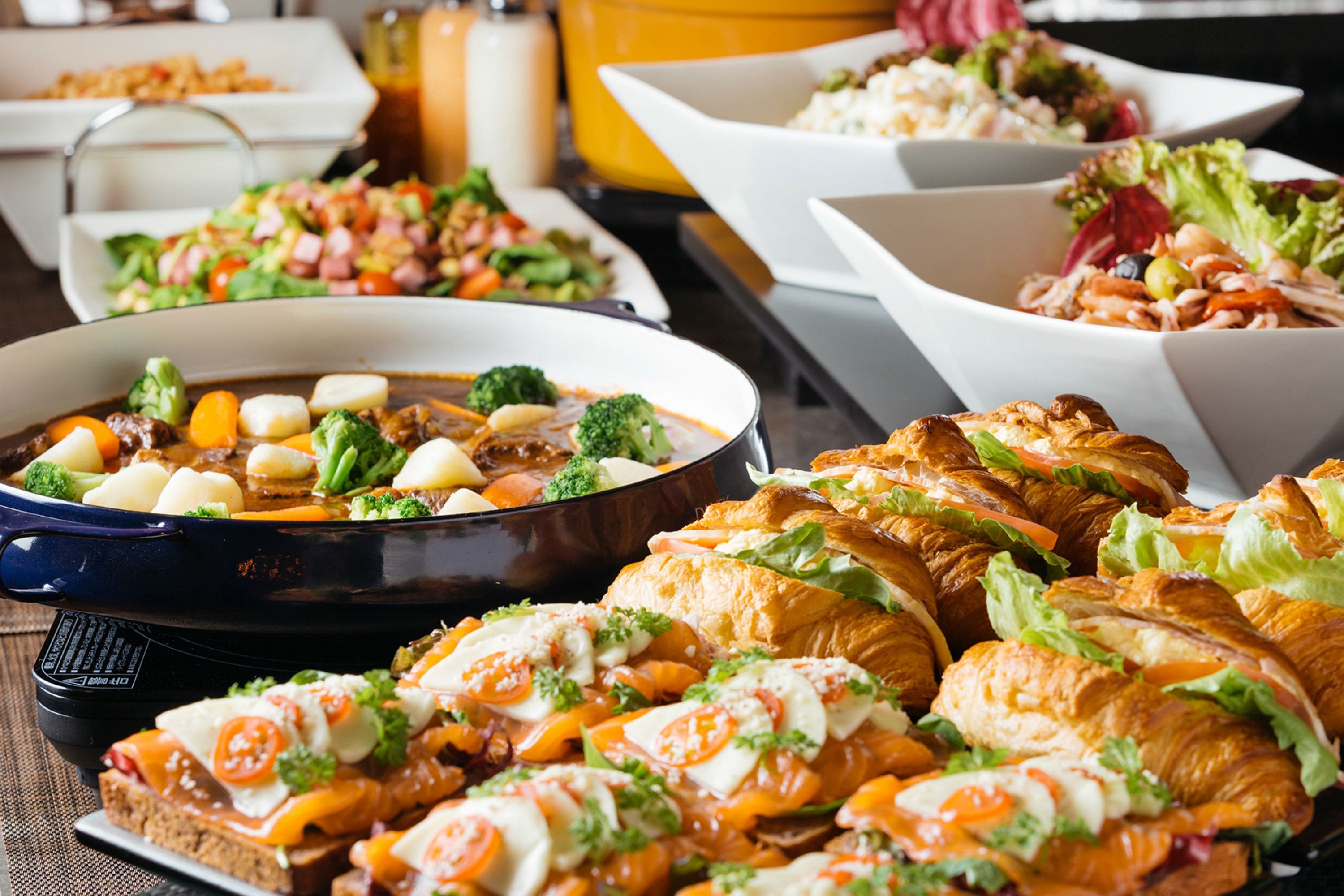 A buffet with various dishes including a seafood dish, salads, and sandwiches.