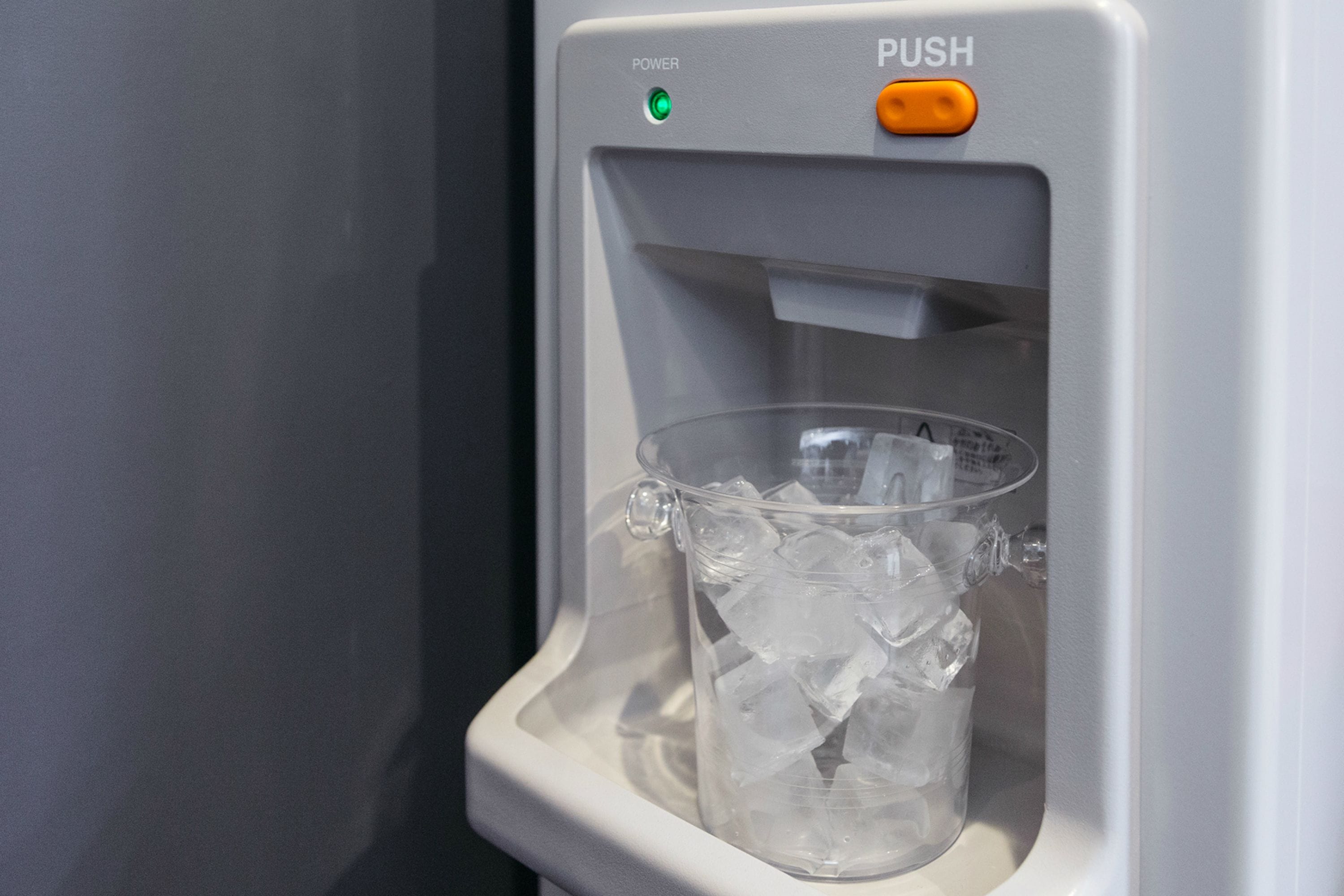 A water dispenser with a clear plastic cup filled with ice cubes.