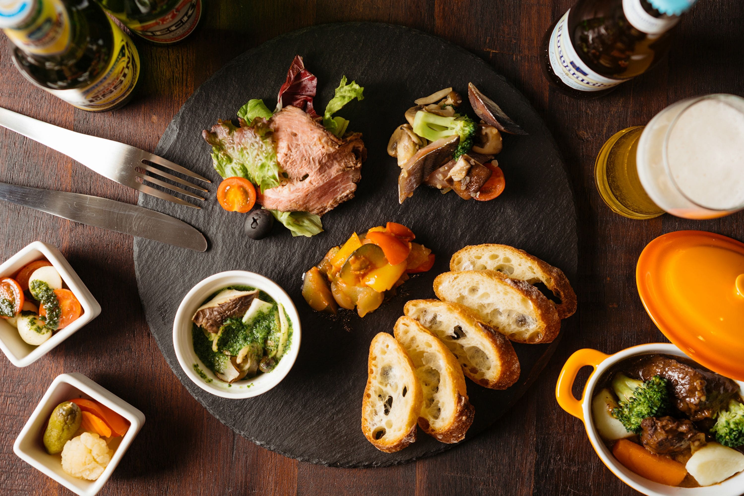 A dining table with a variety of dishes including meat, vegetables, and bread.