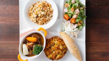 A meal consisting of a bowl of soup, a salad, a piece of bread, and a small pastry on a white plate.
