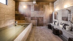 A modern bathroom with a large bathtub, a shower area, and a vanity with a mirror. - Sakura Terrace The Atelier (Kyoto)
