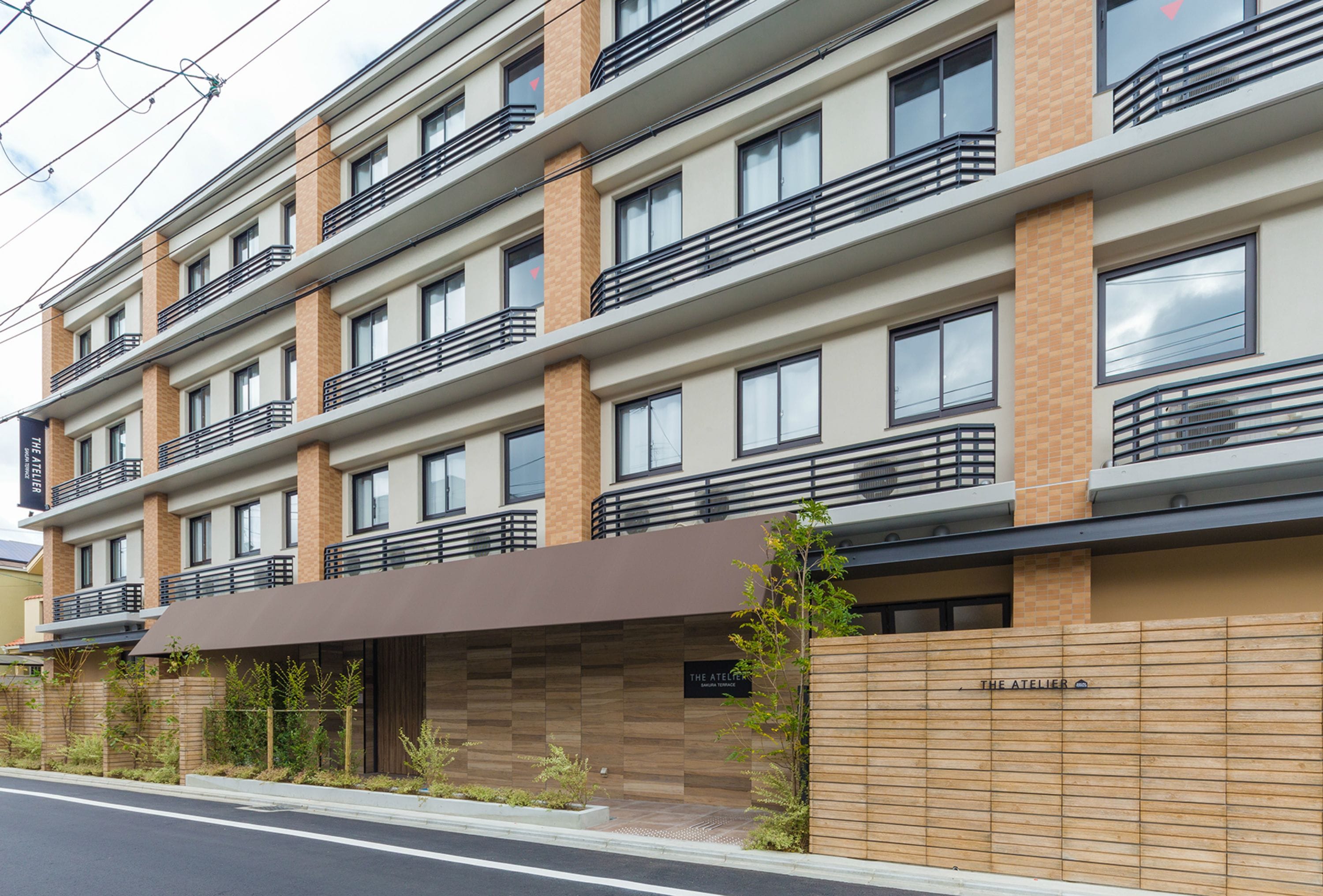 Un hotel de varios pisos con balcones, una fachada moderna y un letrero que dice 'The Atelier'.