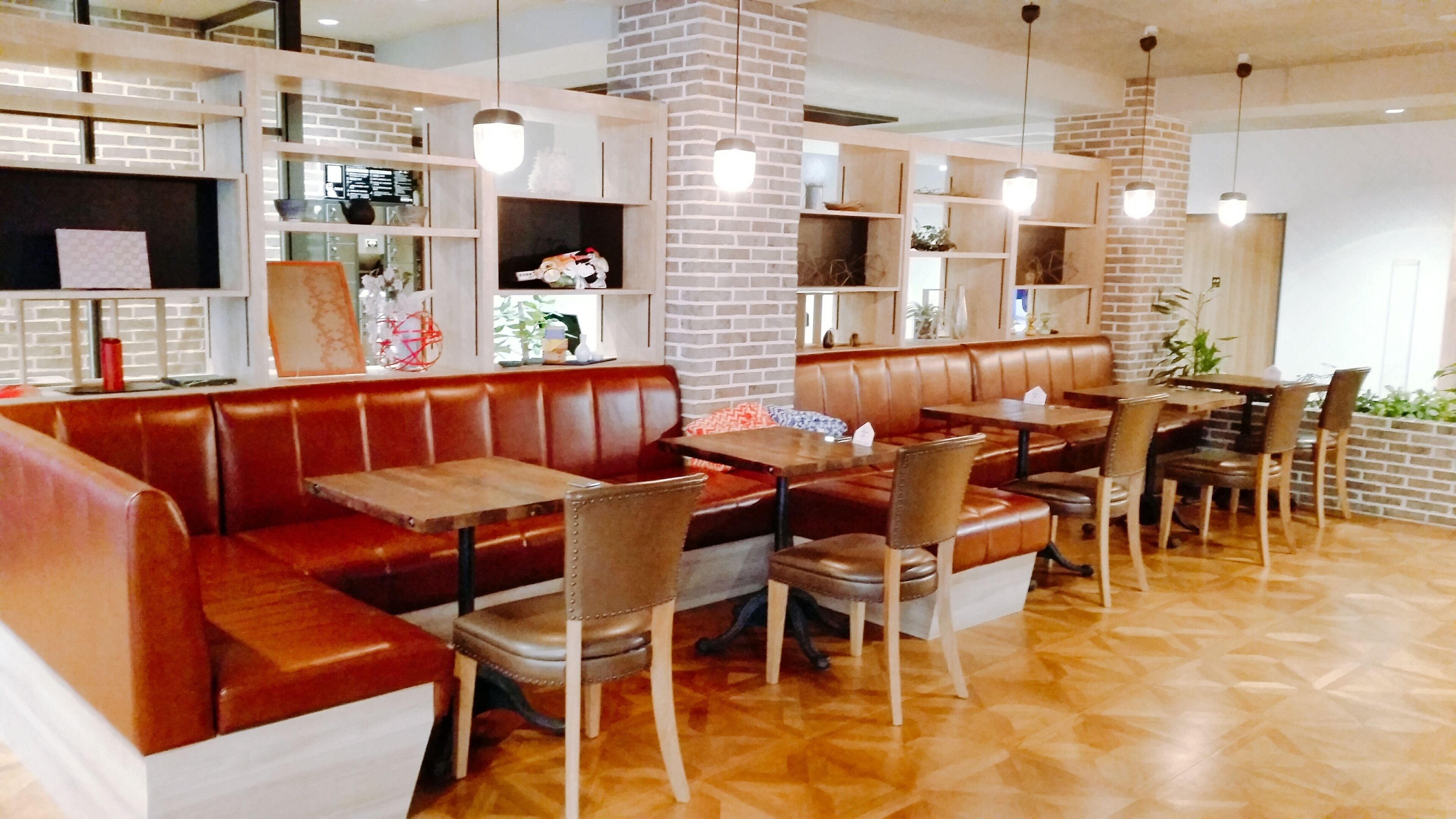 Un restaurante con cabinas de cuero y mesas de madera, paredes de ladrillo y lámparas colgantes.