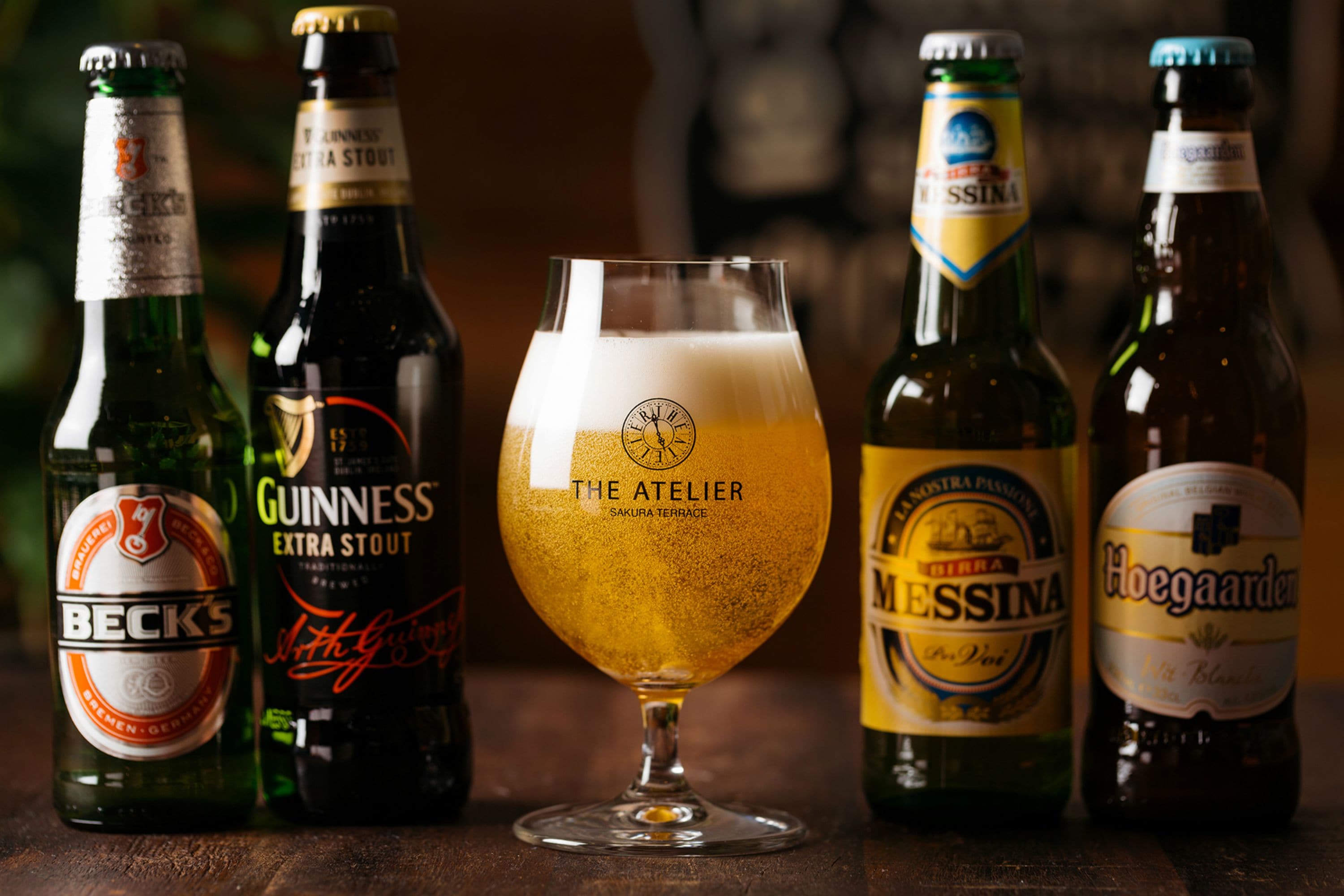 Varias botellas de cerveza y un vaso de cerveza sobre una superficie de madera.