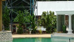 A pool area with a stone structure, a white building, and green foliage. - Hsaung Thazin Hotel Nay Pyi Taw (Oattara Thiri Township)