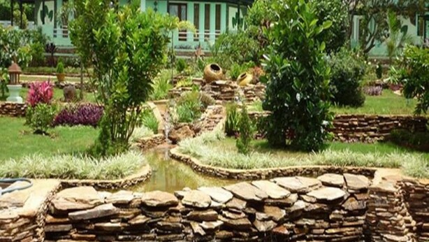 A garden with a pond, stone walls, and green-roofed buildings. - Hsaung Thazin Hotel Nay Pyi Taw (Oattara Thiri Township)
