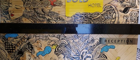 A hotel reception area with a 'WELCOME' sign and 'BOLD HOTEL' branding.
