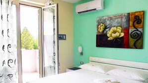 Habitación de hotel con cama, un cuadro en la pared y un equipo de aire acondicionado.