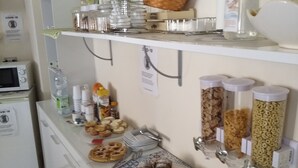 Una cocina con estantes llenos de alimentos, un microondas y un refrigerador.