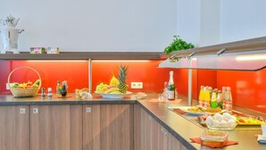 A breakfast bar with a variety of fruits, beverages, and condiments. - City Hotel Wetzlar (Wetzlar)
