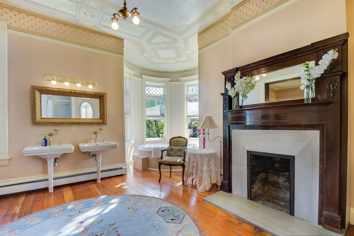 A room with two sinks, a fireplace, and a large mirror.