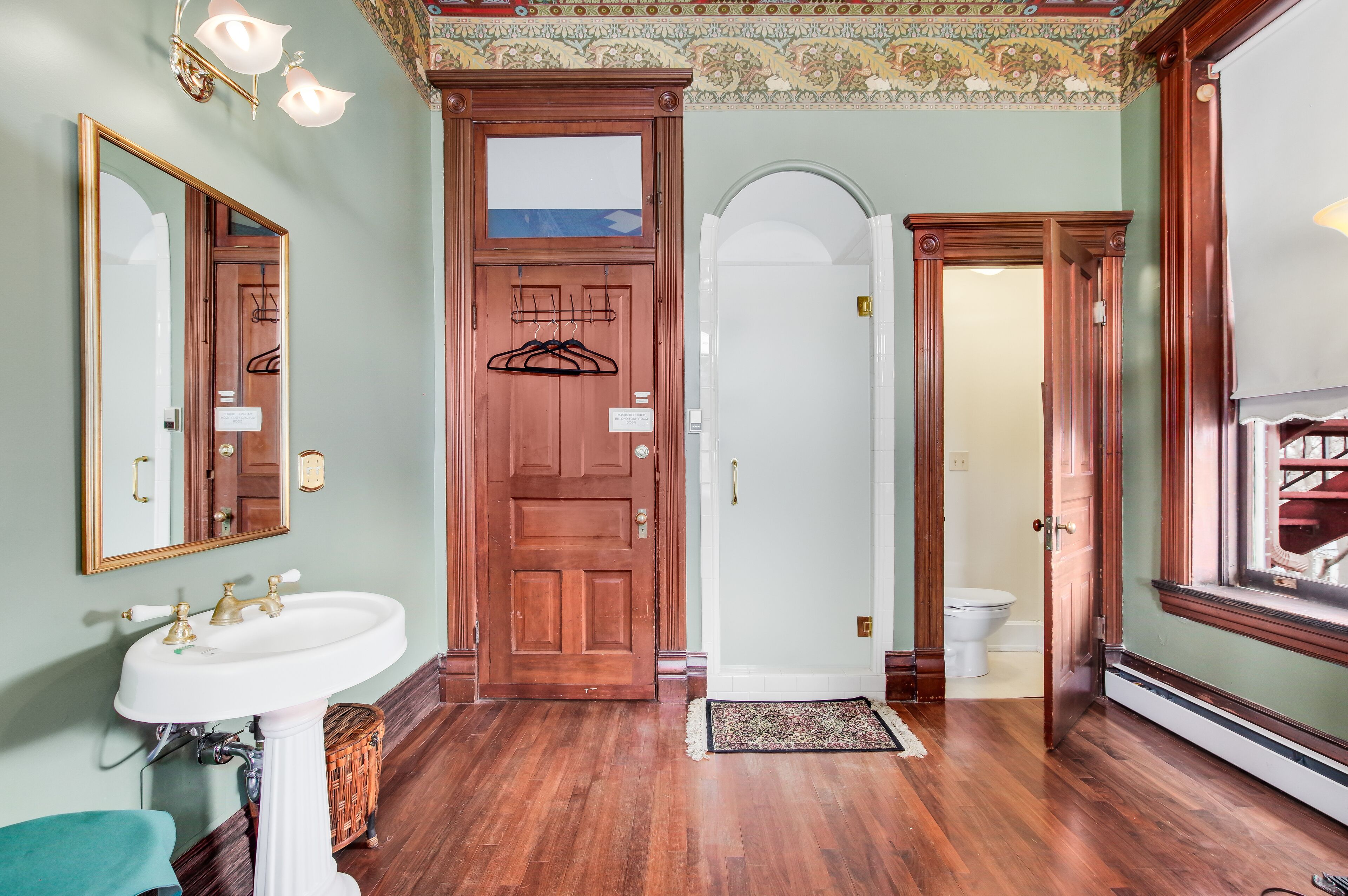 A bathroom with a wooden door, a white sink, and a mirror.