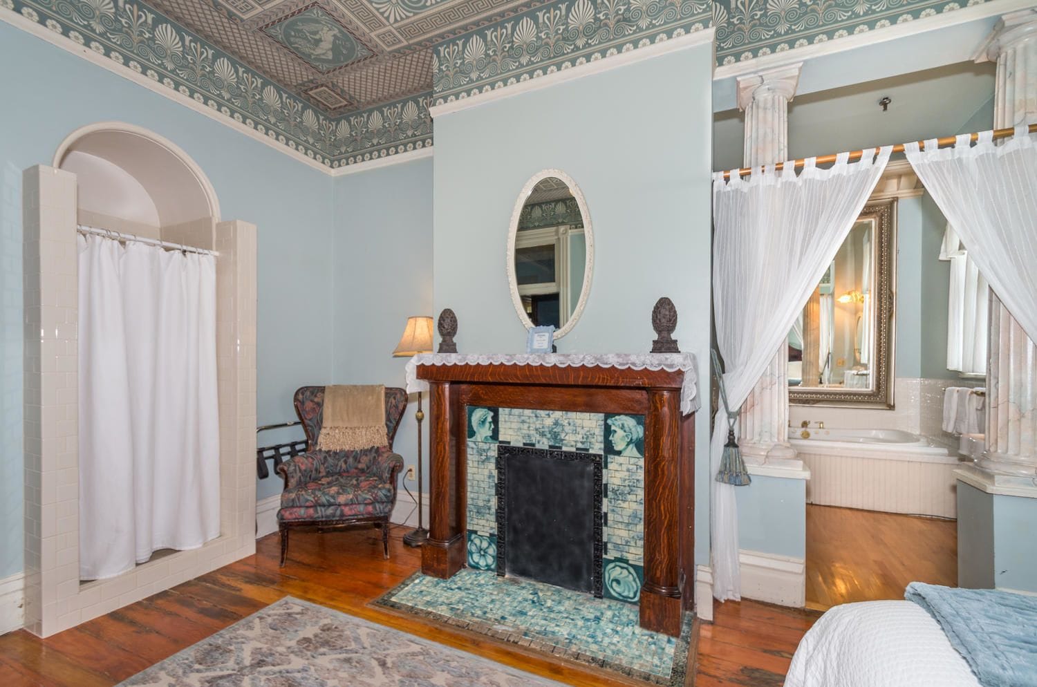 A room with a fireplace, a chair, a bed, and a mirror.