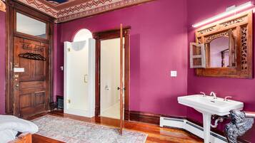 A room with a wooden door, a white sink, and a mirror with ornate details.