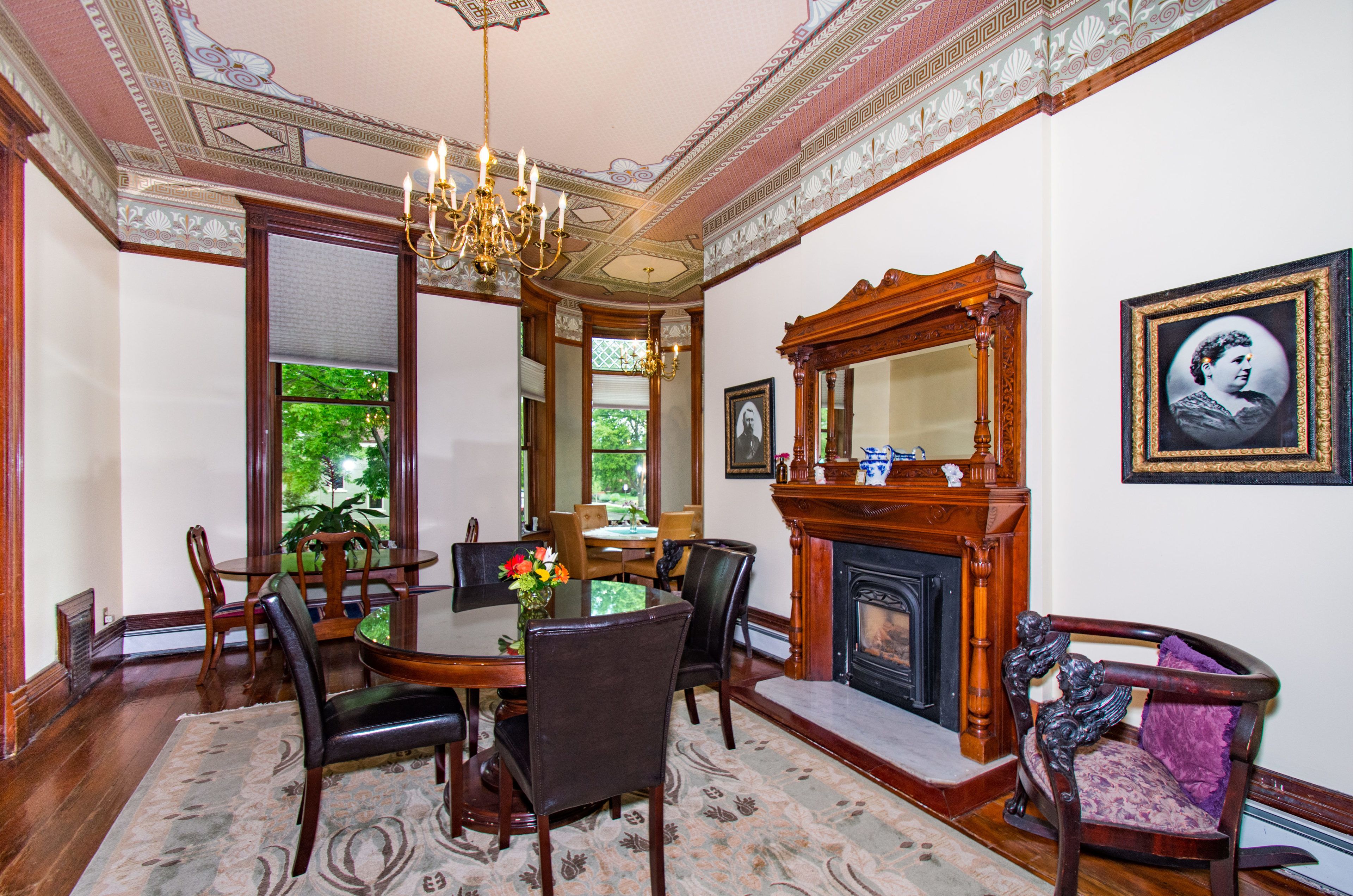 A dining room with a chandelier, wooden furniture, and a fireplace.