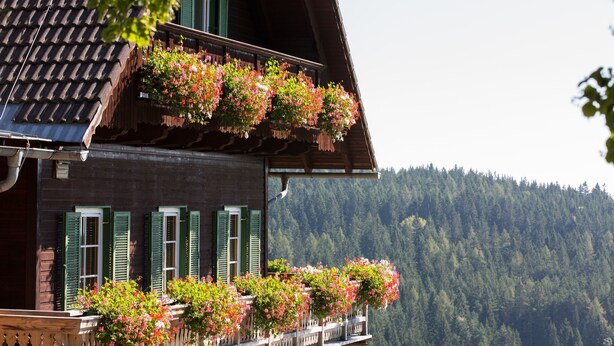 A wooden building with green shutters and flower boxes on the balcony. - Der Klugbauer (Sankt Stefan ob Stainz)