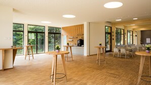A spacious room with wooden flooring, large windows, and a kitchen area. - Der Klugbauer (Sankt Stefan ob Stainz)