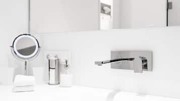 A modern bathroom with a white sink, a round mirror, a soap dispenser, and a towel.